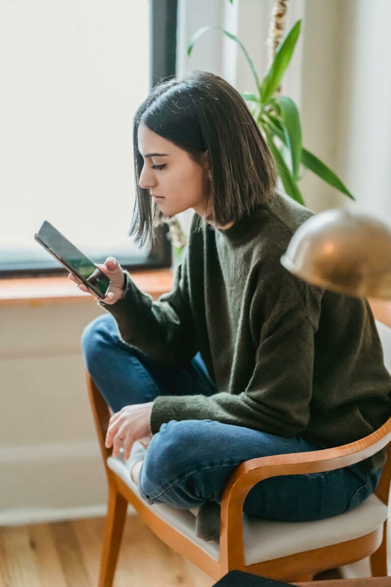 Young woman on her phone by herself in a corner: Tips for Women Struggling with Pornography